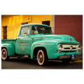 Vintage turquoise truck with white roof parked in front of a yellow building.
