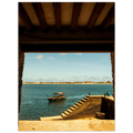 View of a dock with a boat on a body of water, framed by wooden beams.