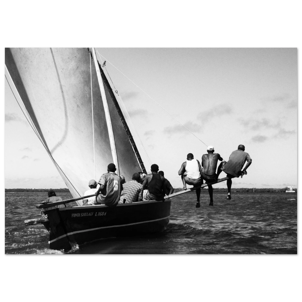 Black and white photo of a group of men on a wooden sailing boat.