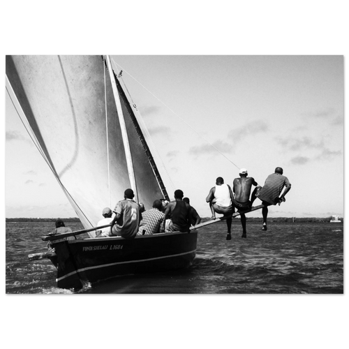 Black and white photo of a group of men on a wooden sailing boat.