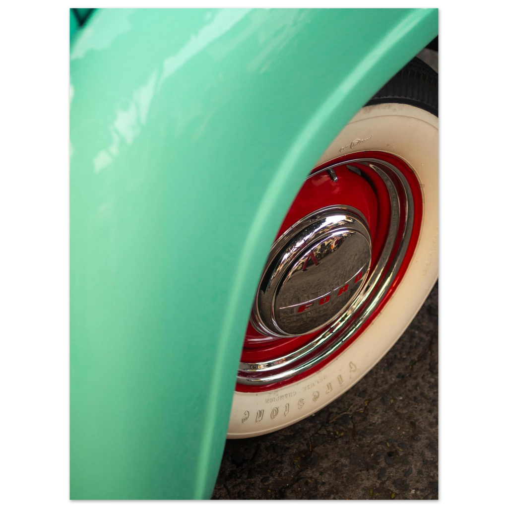Close-up of a green vehicle's wheel with a red rim and white wall tire.