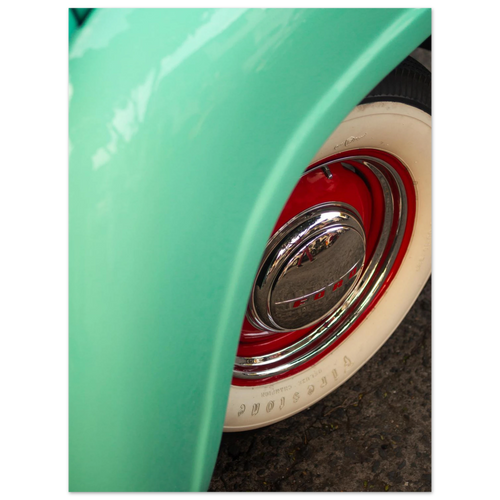 Close-up of a green vehicle's wheel with a red rim and white wall tire.